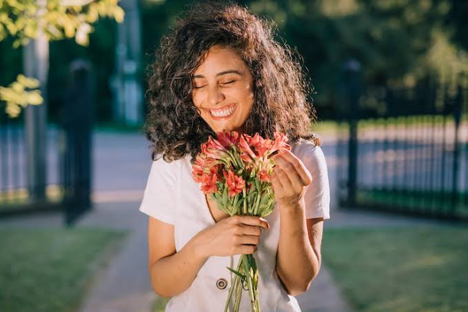Femme souriante en extérieur, illustrant l’inclusion numérique et les communautés rapprochées grâce à la technologie